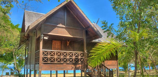 Timber Executive King Chalet on stilts with a carved veranda, among trees beside the sea, Mataking Reef Resort